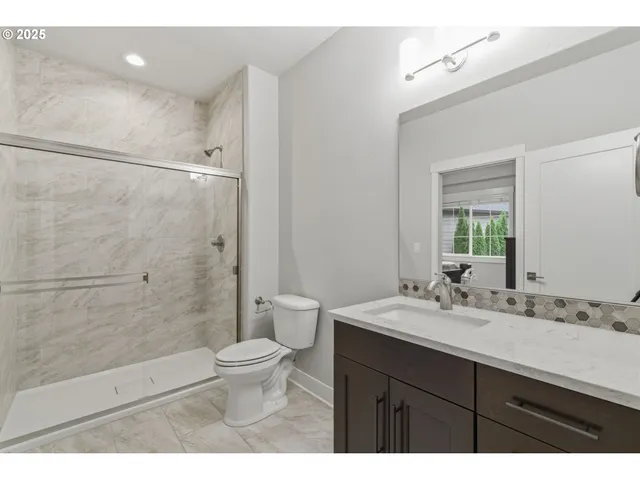 a bathroom with a sink a toilet a mirror and shower