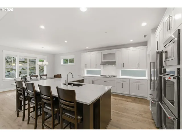 a open dining room with stainless steel appliances kitchen island granite countertop a table chairs and a refrigerator