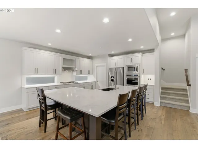 a kitchen with stainless steel appliances kitchen island granite countertop a table chairs and wooden floor