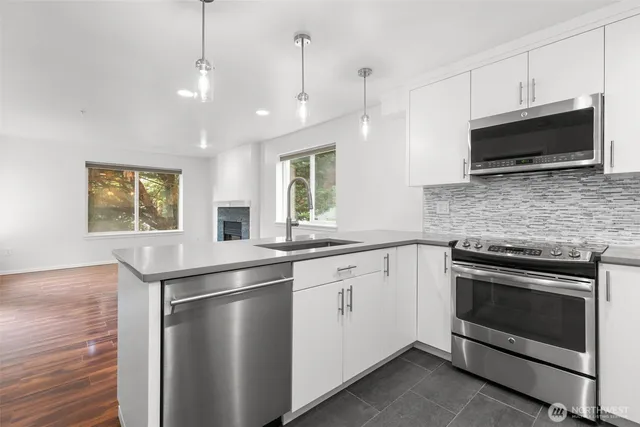 a kitchen with stainless steel appliances granite countertop a stove microwave and a sink