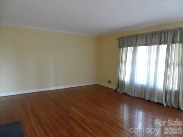 an empty room with wooden floor and windows with curtains view