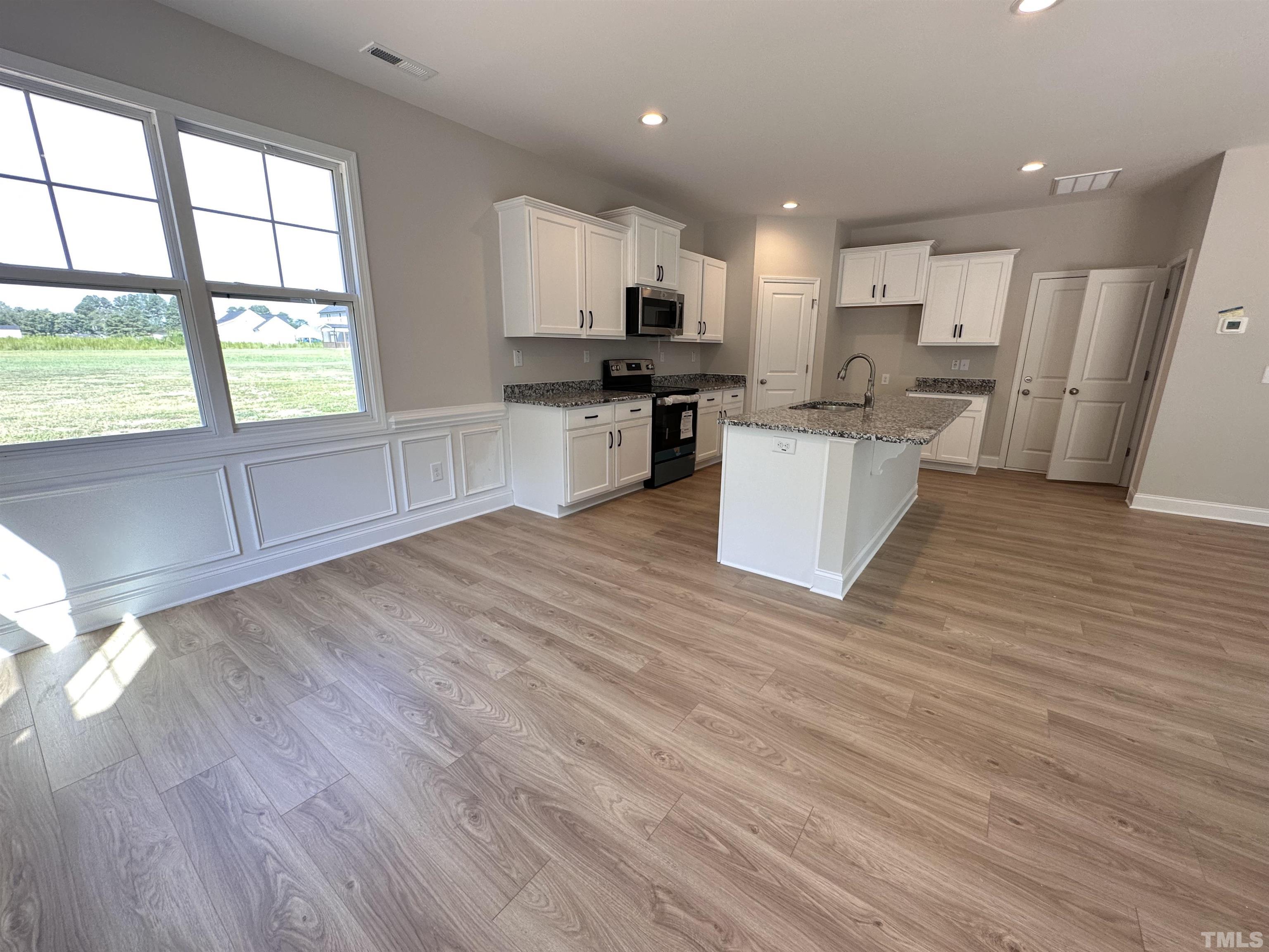 386 Jackson Pond Drive Smithfield, NC 27577 - Photo 3 of 10 a large kitchen with kitchen island a stove a refrigerator a sink and a microwave oven on the wooden floor