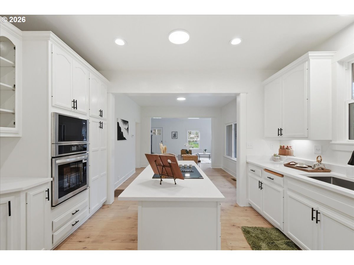 1313 Hining Road Winlock, WA 98596 - Photo 20 of 46 a kitchen with stainless steel appliances kitchen island granite countertop a refrigerator a stove a sink dishwasher and white cabinets with wooden floor