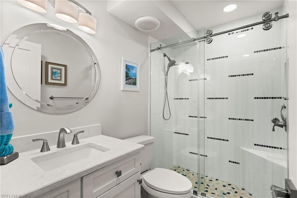 1021 3rd Street South, Unit 108 Naples, FL 34102 - Photo 21 of 31 a bathroom with a granite countertop sink toilet a mirror a vanity and shower