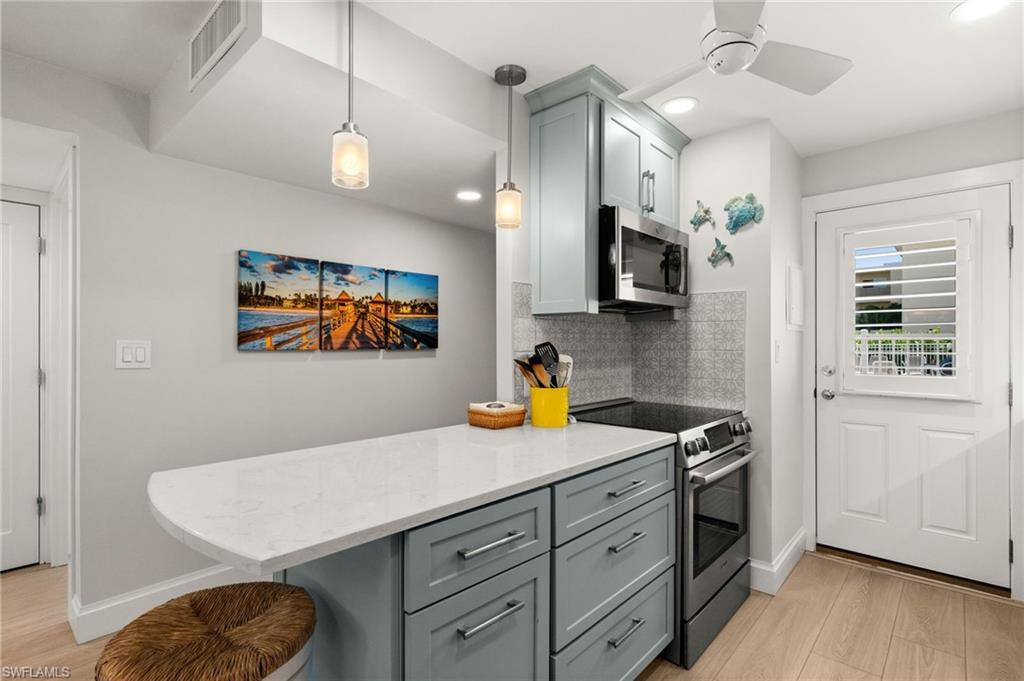 1021 3rd Street South, Unit 108 Naples, FL 34102 - Photo 5 of 31 a kitchen with a sink a stove and a wooden floor