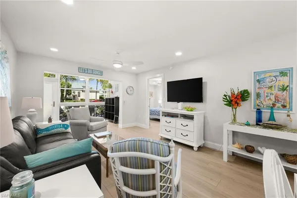 a living room with furniture a flat screen tv and kitchen view