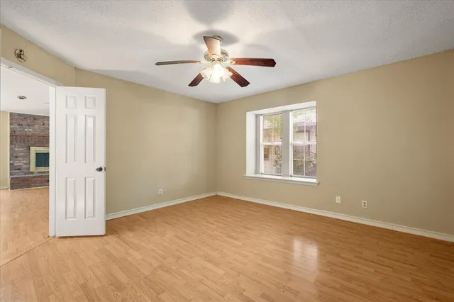 an empty room with wooden floor chandelier fan and windows