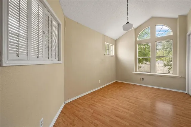 a view of an empty room with a window and wooden floor