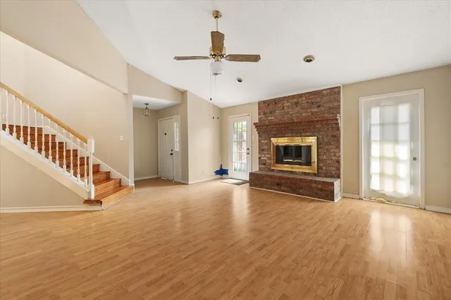 a view of an empty room with wooden floor fireplace and a window