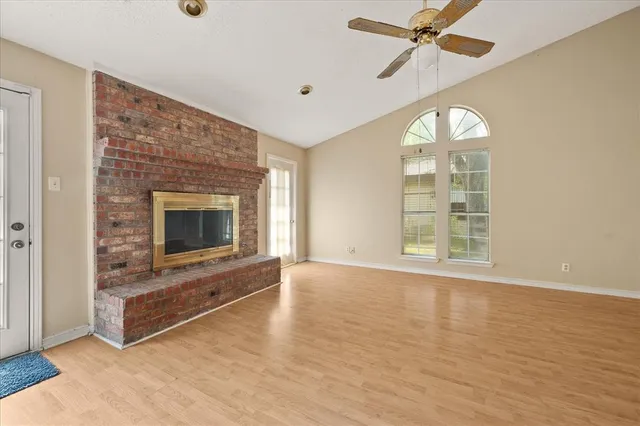 an empty room with windows fireplace and a ceiling fan