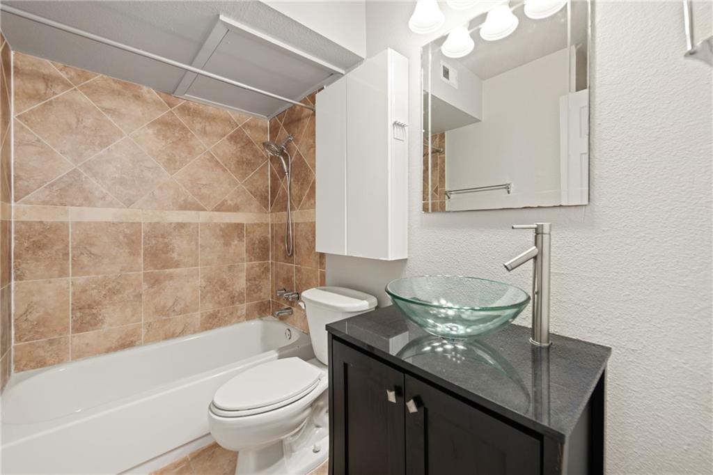 2020 South Congress Avenue, Unit 1216 Austin, TX 78704 - Photo 16 of 33 a bathroom with a granite countertop sink a toilet and bathtub