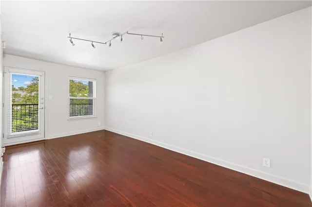 an empty room with wooden floor windows and ceiling fan