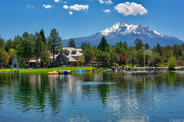 a view of a lake in front of house with a yard and swimming pool