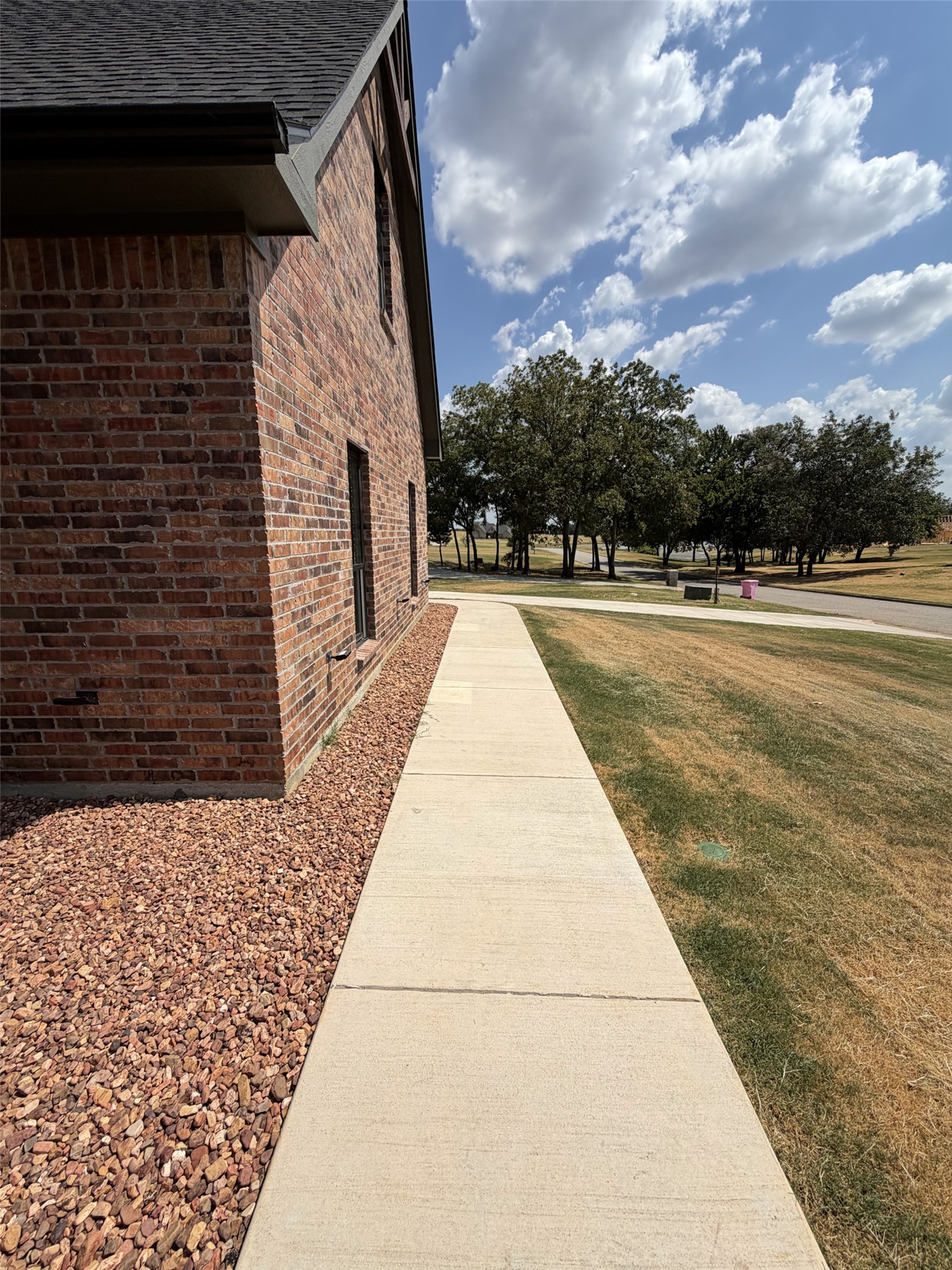 33 Wilderness Road North Calera, OK 74730 - Photo 36 of 39 Brick exterior with dark shingle roofing, concrete walkway, and gravel landscaping