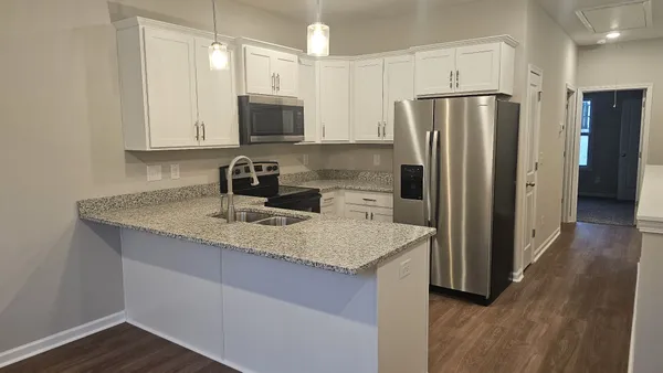 a kitchen with stainless steel appliances granite countertop a refrigerator a sink a stove a microwave and wooden cabinets