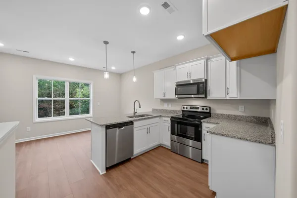 a kitchen with stainless steel appliances granite countertop a stove a sink and a microwave
