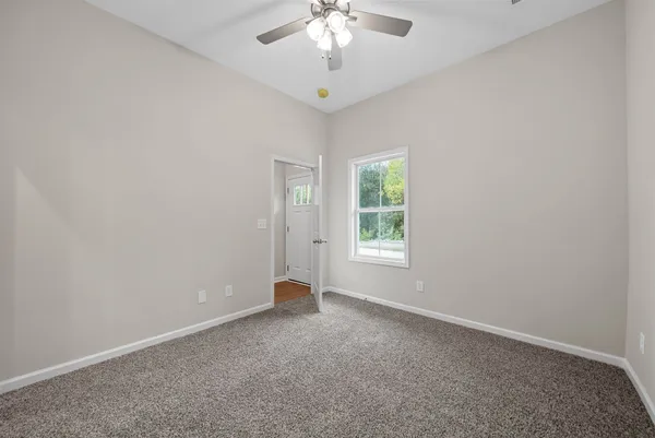 an empty room with a chandelier fan and windows
