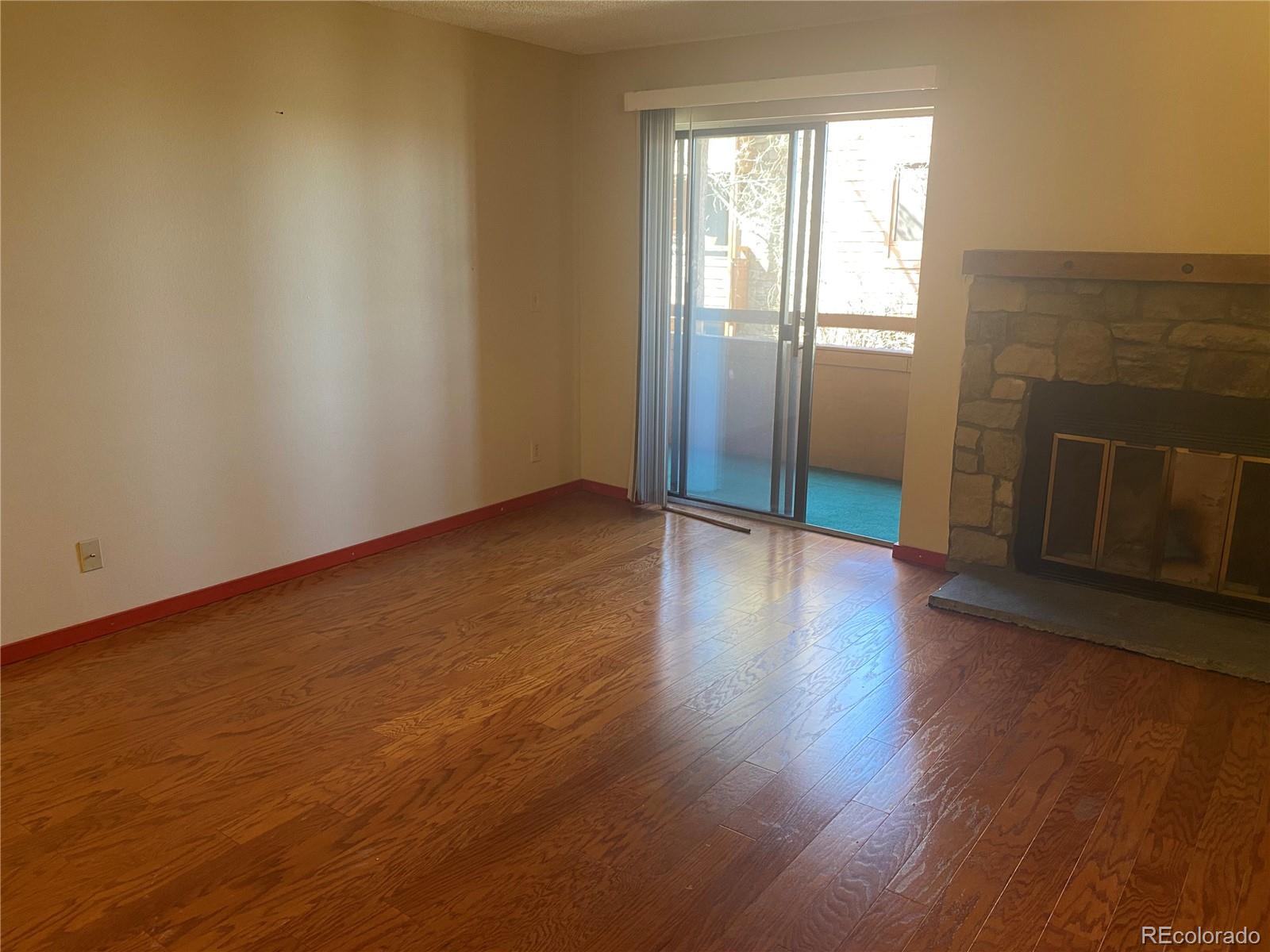 4671 South Decatur Street, Unit 232 Englewood, CO 80110 - Photo 4 of 32 an empty room with wooden floor and fireplace