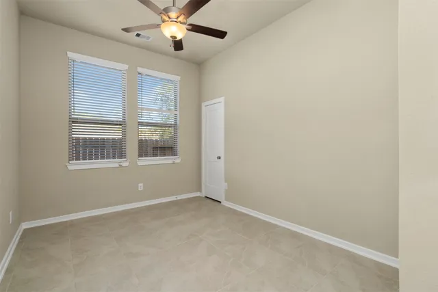 an empty room with windows and fan