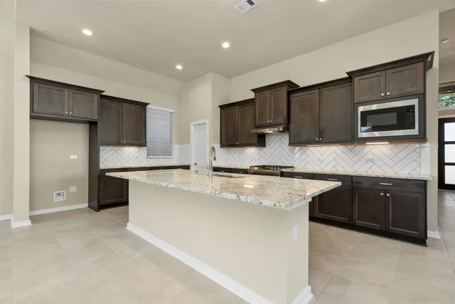 a kitchen with stainless steel appliances granite countertop a stove a sink and a microwave