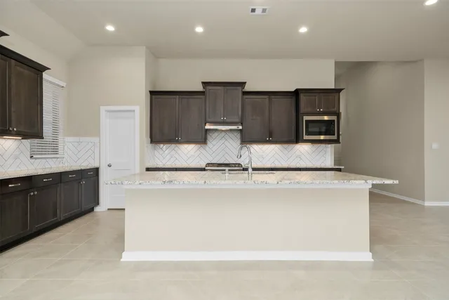 a large kitchen with stainless steel appliances a large counter top a stove and a refrigerator