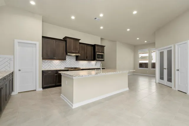 a large kitchen with stainless steel appliances granite countertop a large counter top and a stove top oven