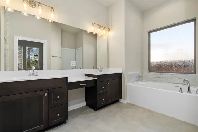 a spacious bathroom with a tub sink double vanity granite and a bathtub