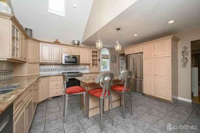 a kitchen with stainless steel appliances granite countertop a stove top oven a sink dishwasher and a refrigerator with the cabinets