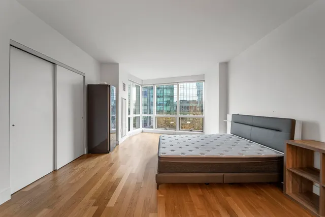 a spacious bedroom with a bed and wooden floor
