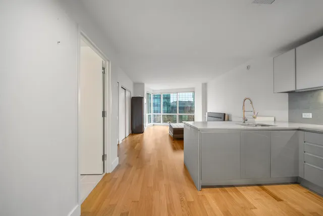 a living room with stainless steel appliances granite countertop a sink wooden floor and a large window