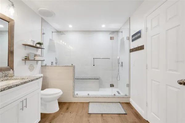 a bathroom with a granite countertop sink a toilet and a shower