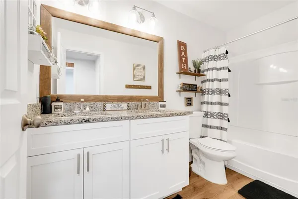 a bathroom with a granite countertop sink a toilet and shower
