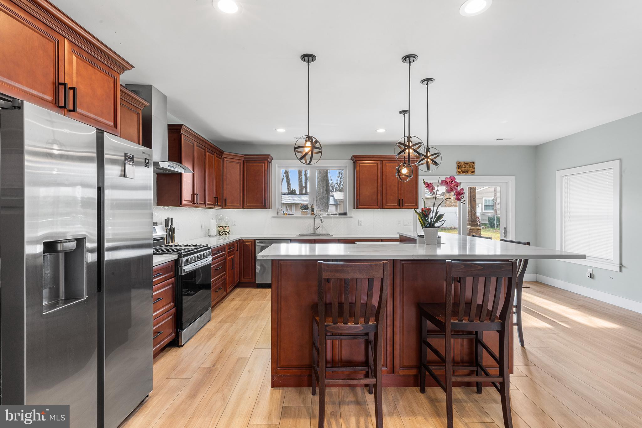 118 Blough Road Fairless Hills, PA 19030 - Photo 8 of 37 a kitchen with stainless steel appliances granite countertop a kitchen island a stove a refrigerator a sink a dining table and chairs with wooden floor
