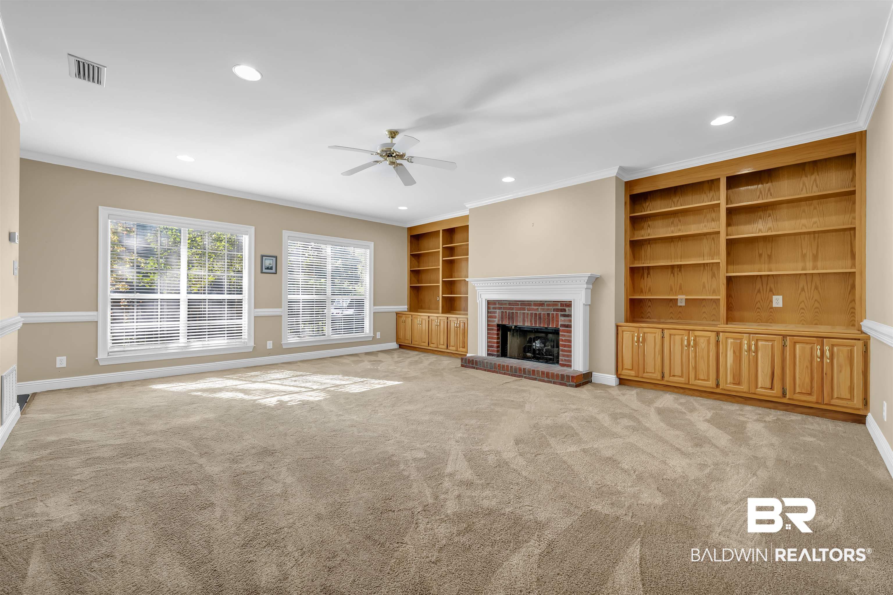 1262 Patrick Street Daphne, AL 36526 - Photo 8 of 35 Unfurnished living room featuring a brick fireplace, built in features, ornamental molding, ceiling fan, and light carpet
