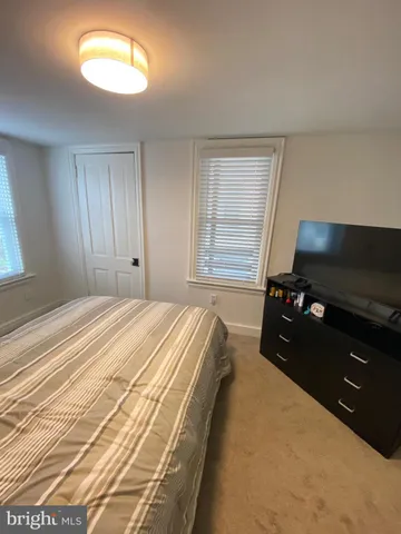 a bedroom with a bed and a flat tv screen on dresser