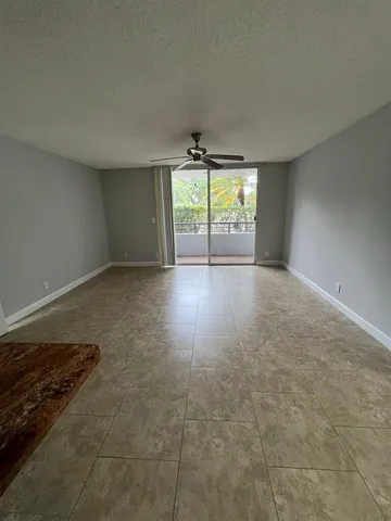 an empty room with windows and ceiling fan