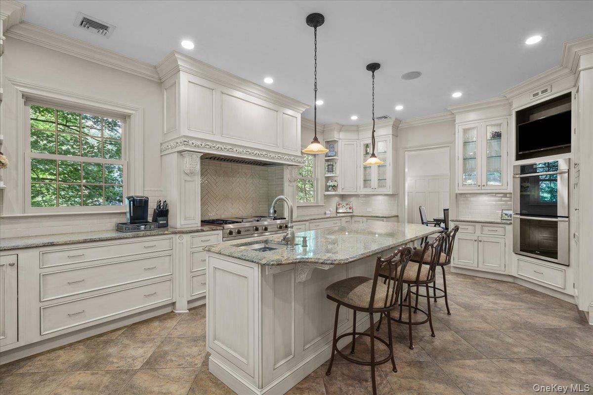 135 Pines Bridge Road Katonah, NY 10536 - Photo 6 of 40 a kitchen with kitchen island granite countertop a sink a center island stainless steel appliances and cabinets