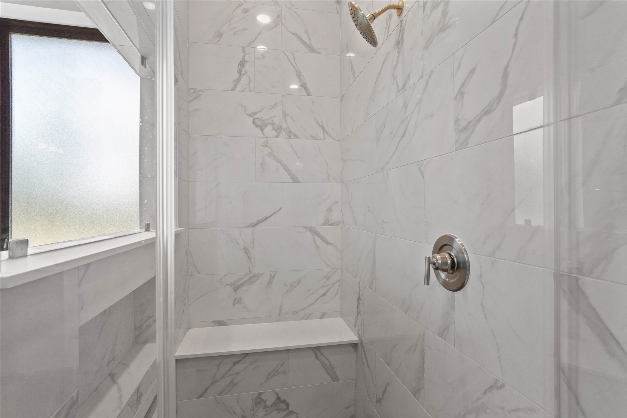551 Black Bronco Road Magnolia, TX 77354 - Photo 32 of 50 Enjoy a spa-like experience in this modern walk-in shower with built-in seat, niche for shower supplies, fixed shower head and elegant porcelain tile surround.