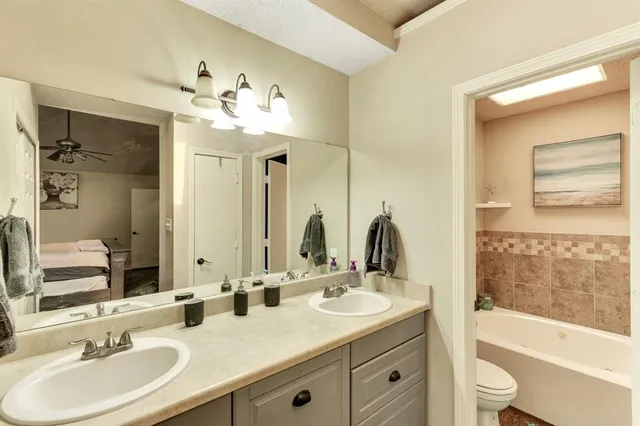 a bathroom with a double vanity sink toilet mirror and bathtub
