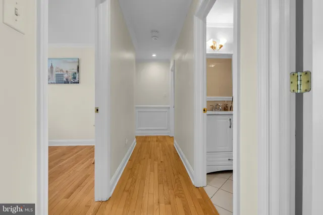 a view of a hallway with wooden floor and a bathroom