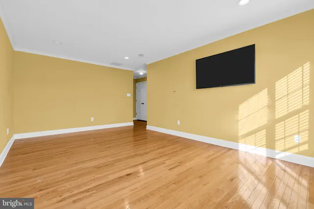 a view of an empty room with wooden floor and a flat screen tv