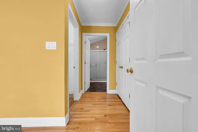 a view of a hallway with wooden floor and a bathroom
