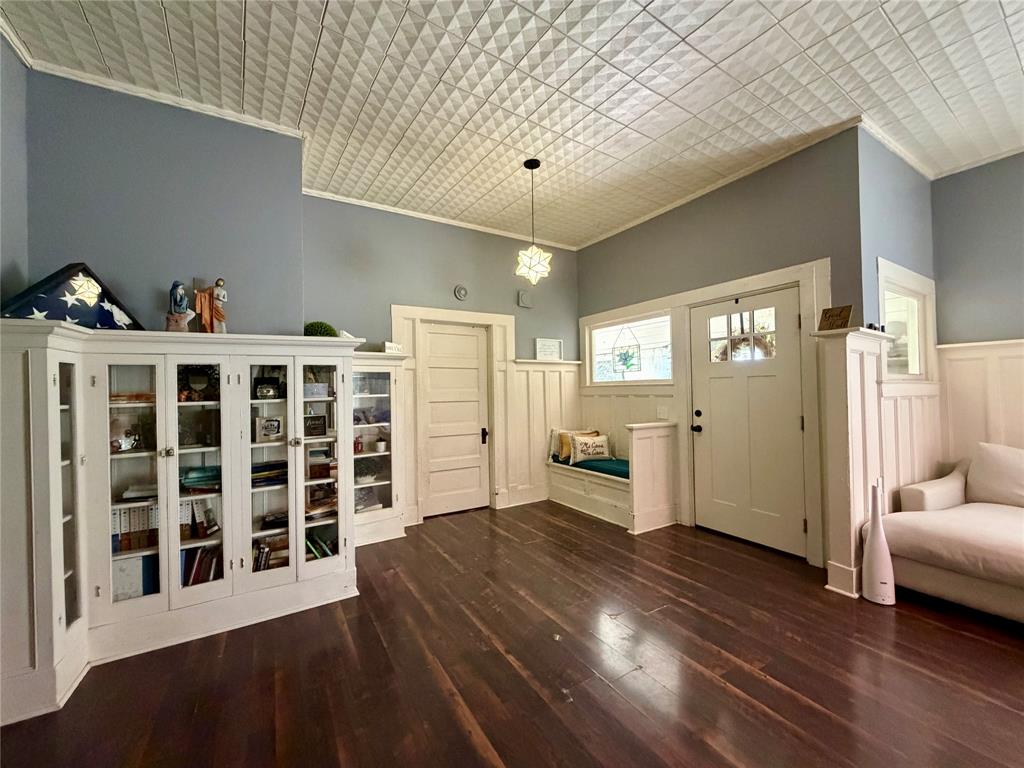 301 Forrest Avenue Cleburne, TX 76033 - Photo 5 of 14 Entryway featuring dark wood-finish flooring, a decorative white tin-panel ceiling, and white wainscoting