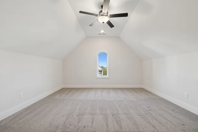 a view of an empty room and chandelier fan