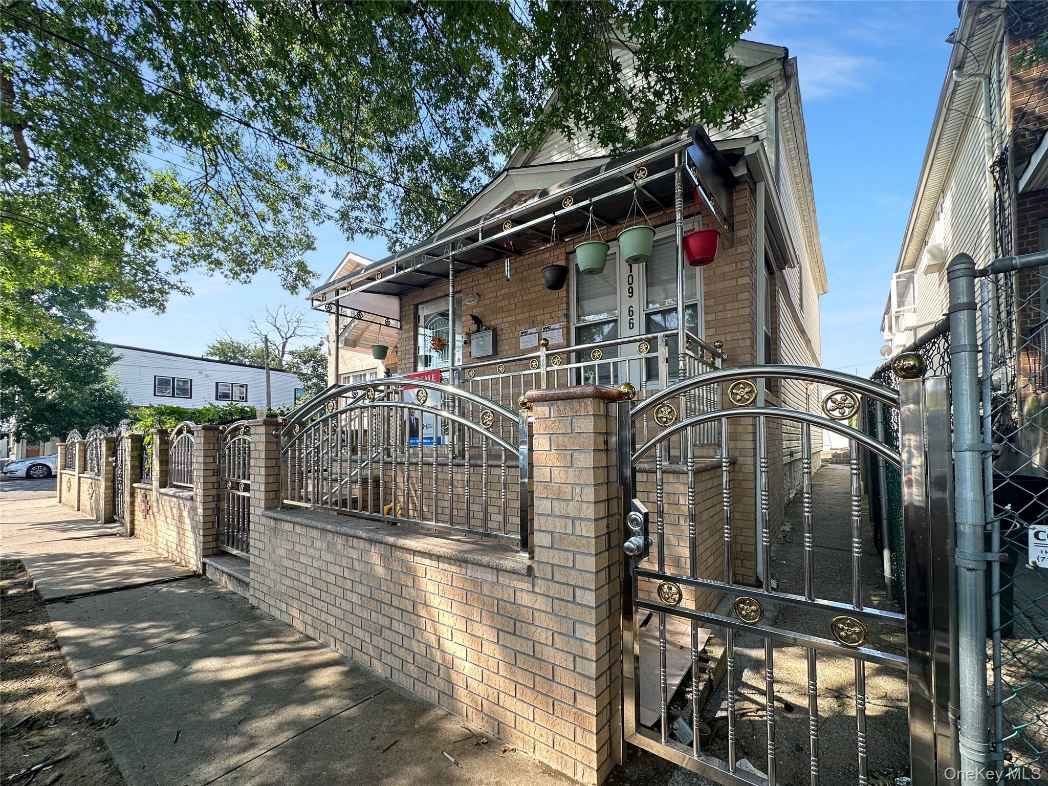 View of front of home featuring a gate, a fenced front yard, brick siding, and covered porch