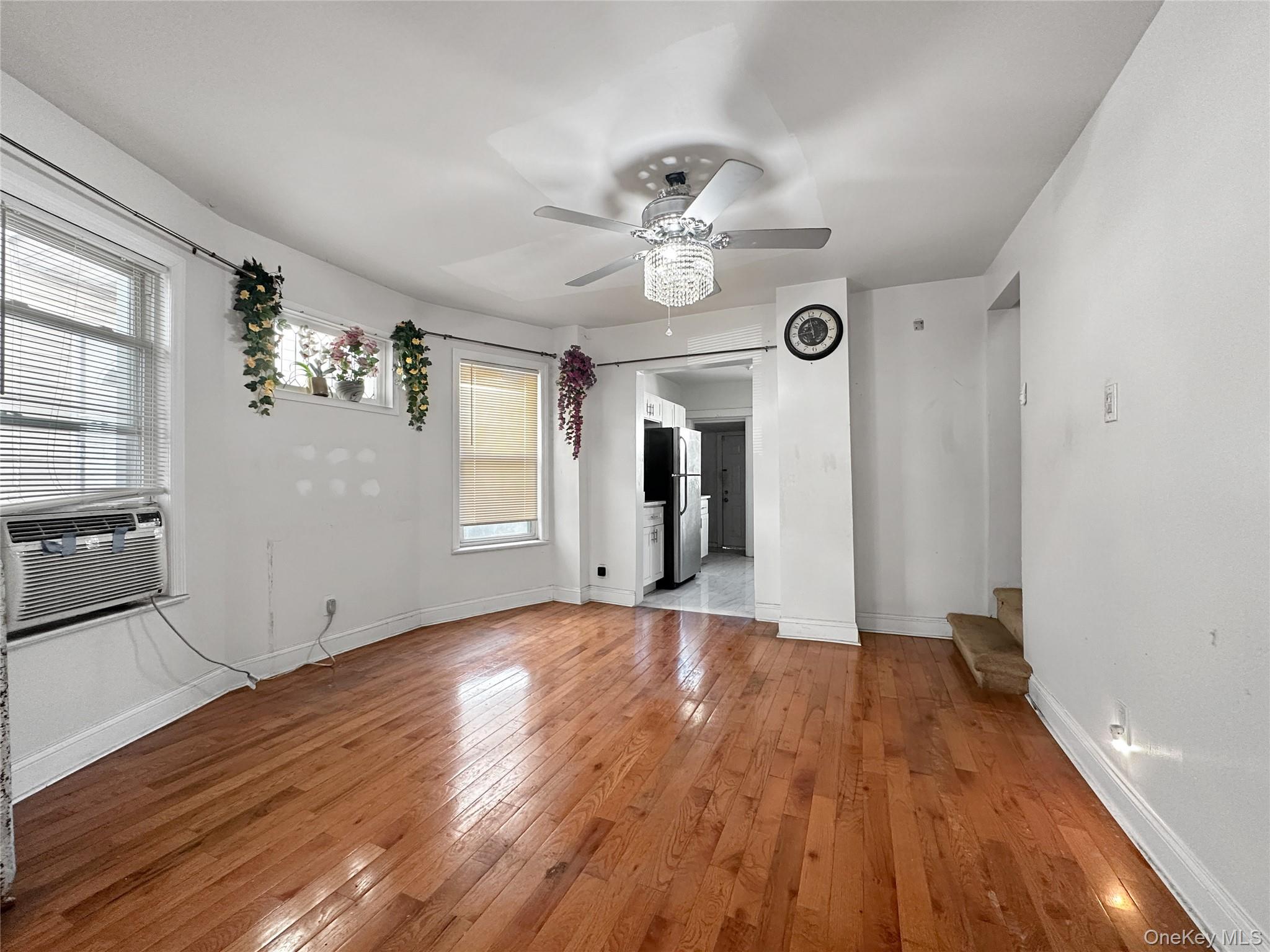 109-66 153rd Street Queens, NY 11433 - Photo 9 of 15 Unfurnished living room featuring hardwood / wood-style floors, a ceiling fan, stairs, and cooling unit