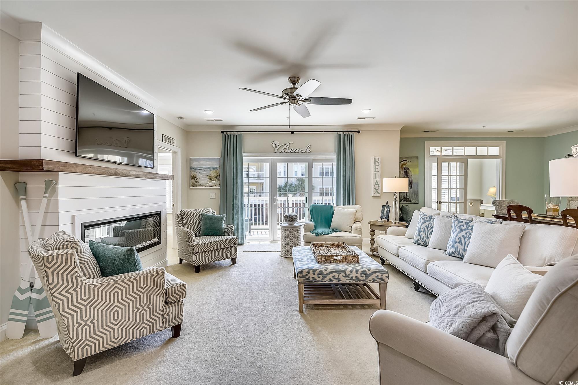 1029 Ray Costin Way, Unit VILLA 906 Murrells Inlet, SC 29576 - Photo 10 of 40 Living area with carpet flooring, crown molding, healthy amount of natural light, ceiling fan, and a glass covered fireplace