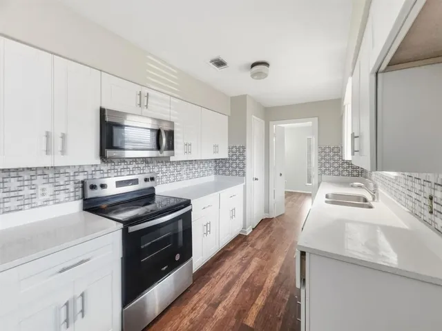 a large white kitchen with stainless steel appliances