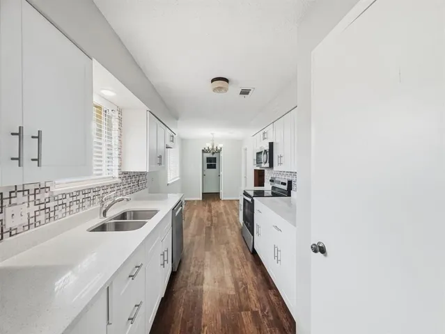 a large white kitchen with a sink and cabinets