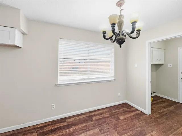 a view of a room with a hanging light and kitchen view